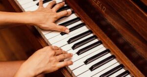 Musician's hands playing wooden piano keys in a high contrast image, capturing musical expression.
