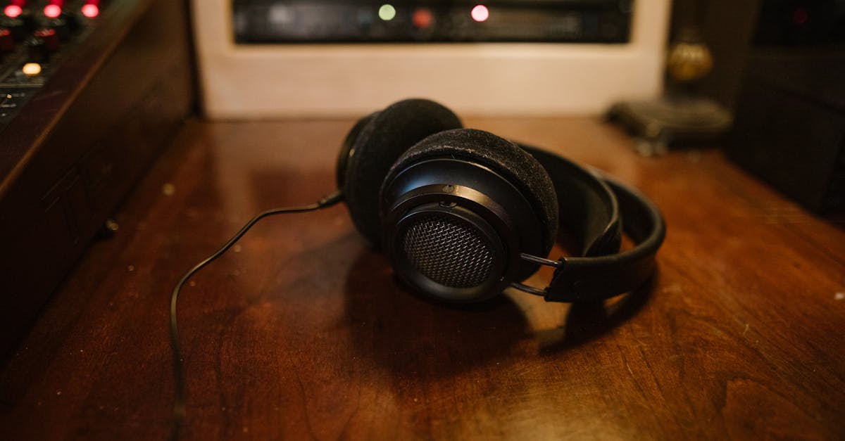 Black headphones resting on wooden desk with studio equipment in background.