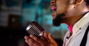 Close-up of a vibrant singer with a vintage microphone performing passionately indoors.